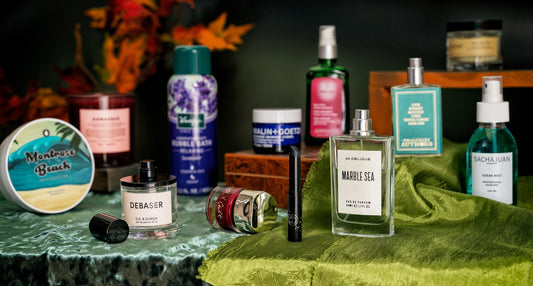 Beauty and grooming products displayed on colorful fabrics with autumn foliage in the background