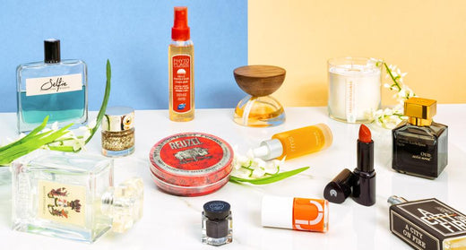 Assortment of fragrances and personal care products arranged on a white table against colorful backgrounds