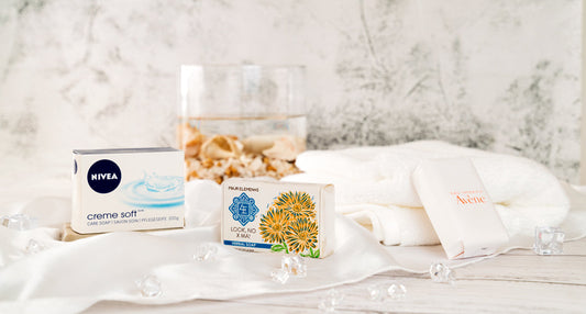 Assorted bar soaps displayed on white towels beside a glass of water and decorative stones