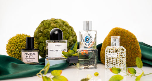 Niche fragrance bottles arranged with moss, greenery, and spring-inspired accents