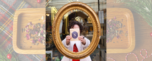 Lisa Frye holds a Gratitude Tea package in an ornate gold mirror at a storefront