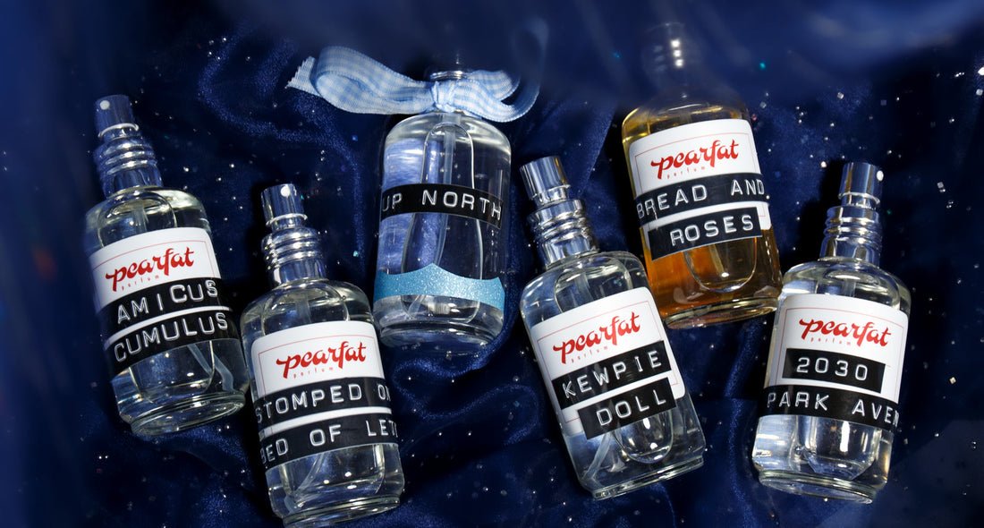 Overhead view of Pearfat Parfum bottles showcasing assorted fragrance labels on dark blue fabric