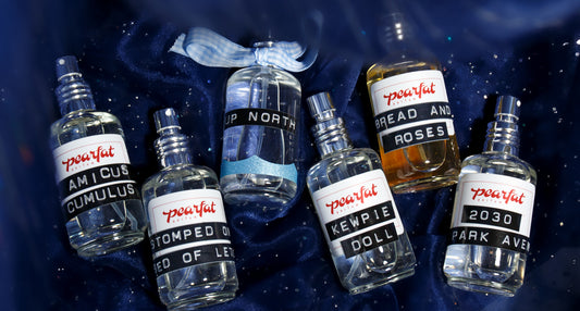 Overhead view of Pearfat Parfum bottles showcasing assorted fragrance labels on dark blue fabric