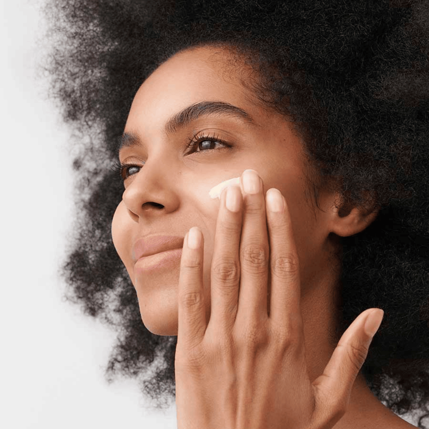Alternate image of model applying cream to face