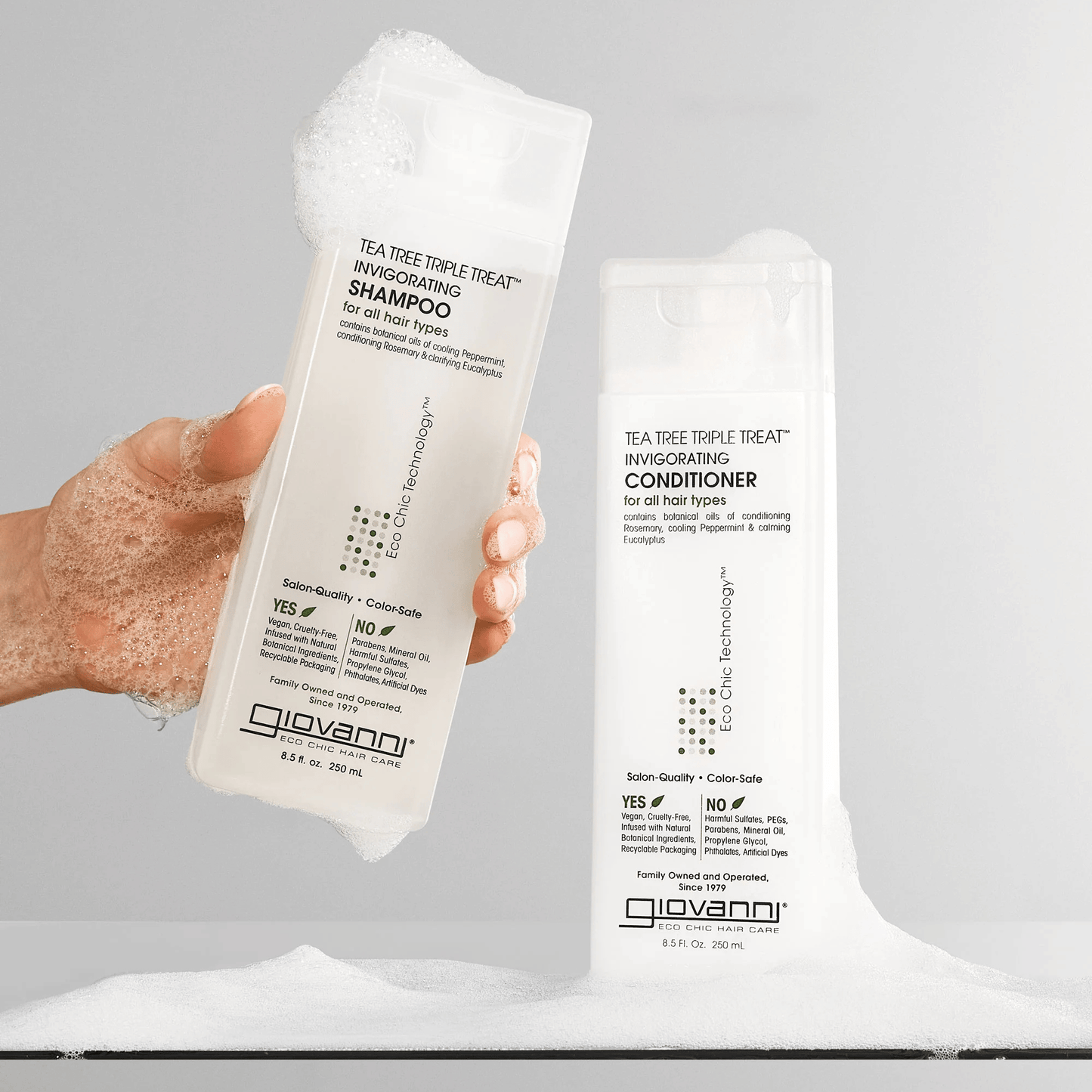 Alternate image of model holding Tea Tree Shampoo and Conditioner